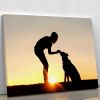A silhouette of a girl sitting outside in the grass with her pet German Shepherd Mix Dog feeding him treats during training in front of a sunsetting s